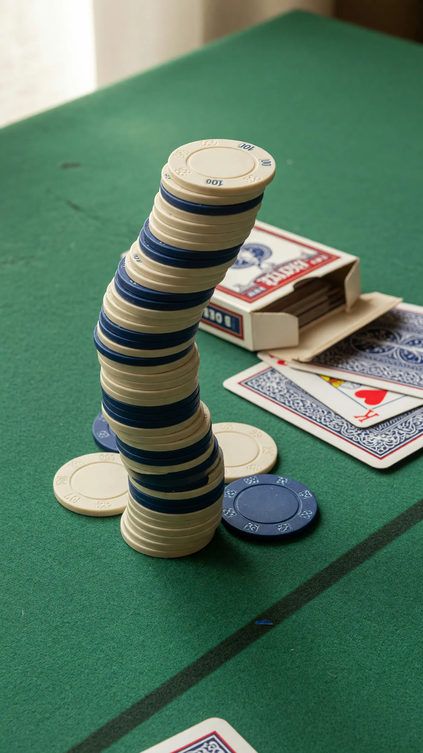 A tall stack of cream and ink-blue chips beside a deck of cards.
