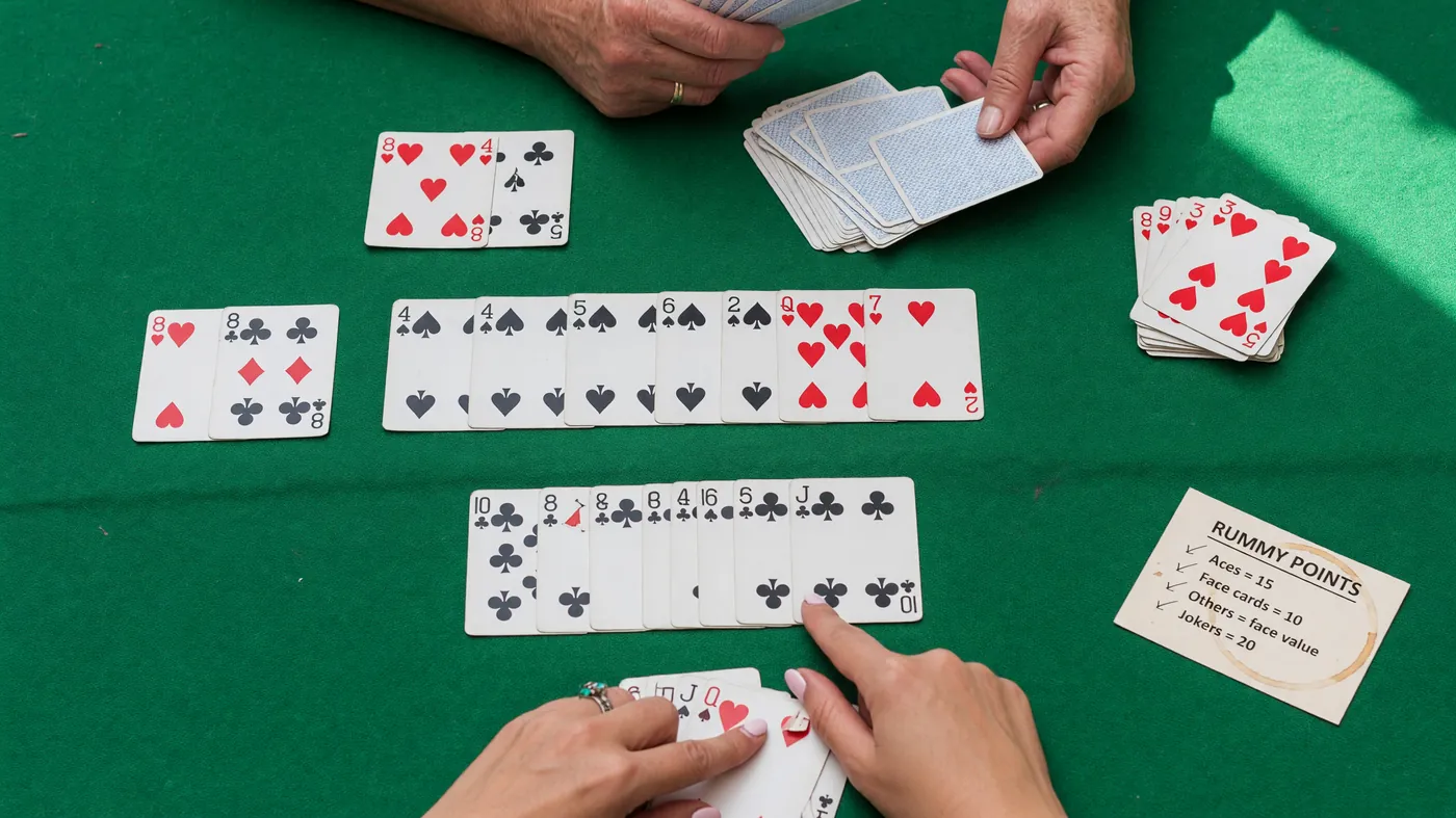 A top-down photograph of a clean meld arrangement on a green baize mat, three sequential cards of one suit in a row beside a colour-run set, soft diffused daylight.